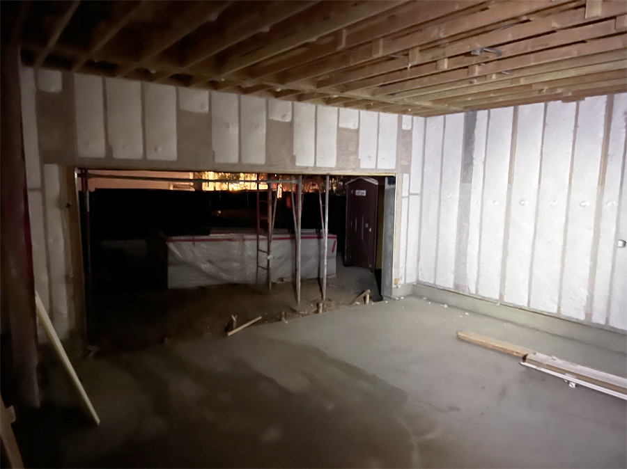 A residential room during renovation with newly installed white foam insulation covering the walls and ceiling, alongside large windows showing the meticulous work of home insulation.